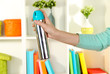 Sprayed air freshener in hand on white shelves background