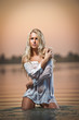 Sexy blonde woman play in white lingerie in a river water