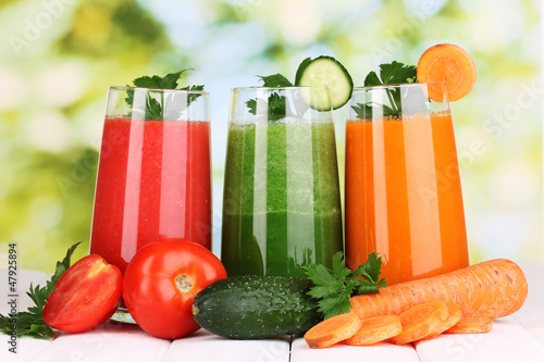 Photo: Fresh vegetable juices on wooden table, on green background Fresh vegetable juices on wooden table, on green background