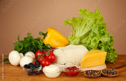 Photo: Ingredients for pizza on wooden table on brown background Ingredients for pizza on wooden table on brown background