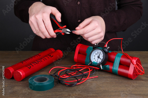 Photo: Human makes timebomb on wooden table on black background Human makes timebomb on wooden table on black background