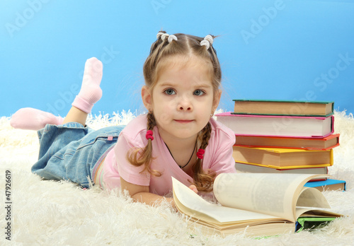 Photo: cute little girl with colorful books, on blue background cute little girl with colorful books, on blue background