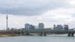 Trains go on railway bridge through river Danube at left stands