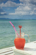 Red cocktail on white table set over ocean