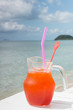 Red cocktail on white table set over ocean
