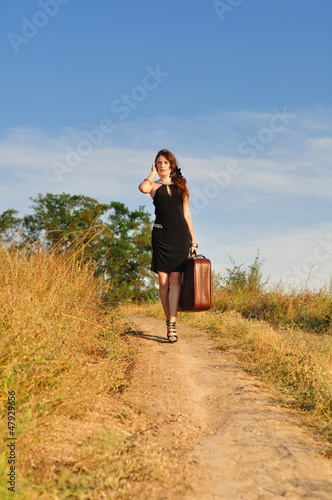Photo: Lonely girl with suitcase at country road Lonely girl with suitcase at country road
