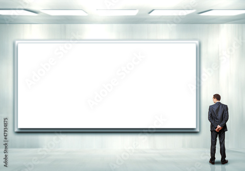 Photo: Business person standing near a blank billboard Business person standing near a blank billboard