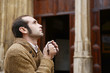 Man praying in church holding prayer beads