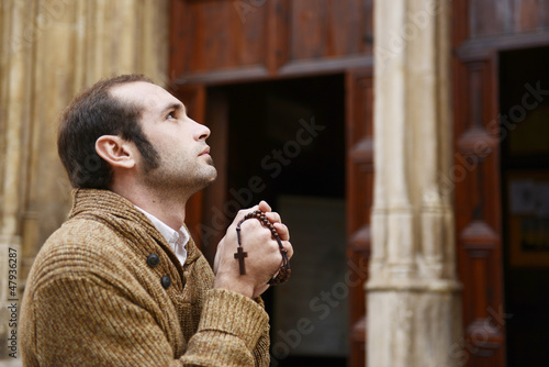 Photo: Man praying in church holding prayer beads Man praying in church holding prayer beads