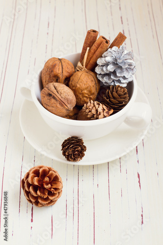Photo: Walnuts and Christmas decor in cup on white tabletop Walnuts and Christmas decor in cup on white tabletop