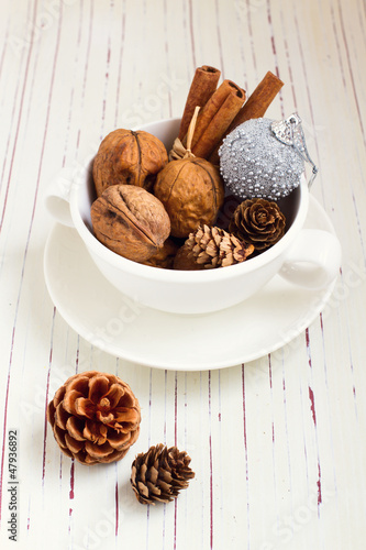 Photo: Walnuts and Christmas decor in cup on white tabletop Walnuts and Christmas decor in cup on white tabletop