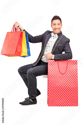 Photo: A smiling elegant guy posing with shopping bags in his hand A smiling elegant guy posing with shopping bags in his hand
