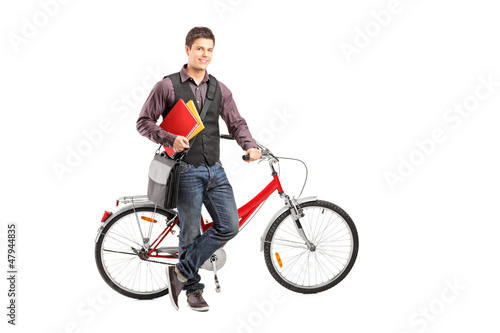 Photo: Smiling student holding books next to a bike Smiling student holding books next to a bike