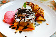 Sweet rolled pancake with banana and ice cream, drizzled with ch