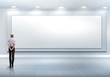 Business person standing near a blank billboard