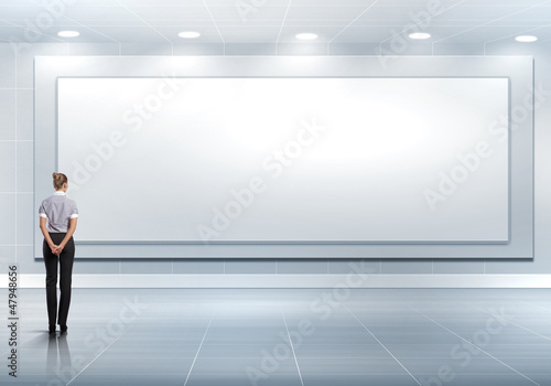 Photo: Business person standing near a blank billboard Business person standing near a blank billboard