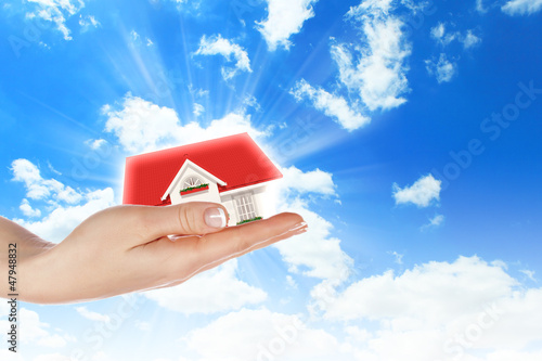 Photo: the house in hands on blue sky the house in hands on blue sky