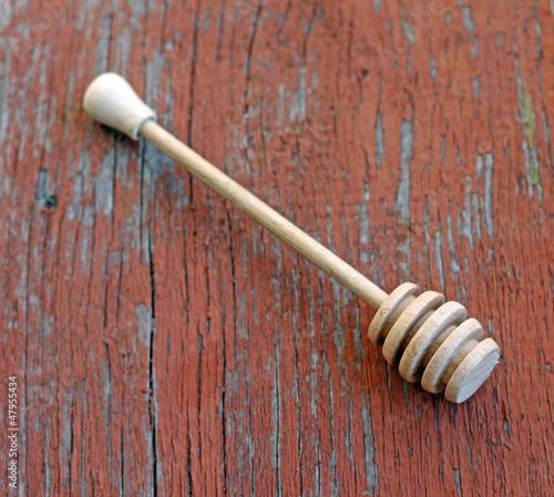 Photo: Wooden honey drizzler on wooden background, close-up Wooden honey drizzler on wooden background, close-up