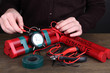 Human makes timebomb on wooden table on black background