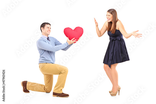 Photo: Smiling male kneeling with red heart and surprised woman Smiling male kneeling with red heart and surprised woman