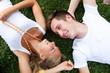 Photo: Young man and woman lying on grass head to head Young man and woman lying on grass head to head