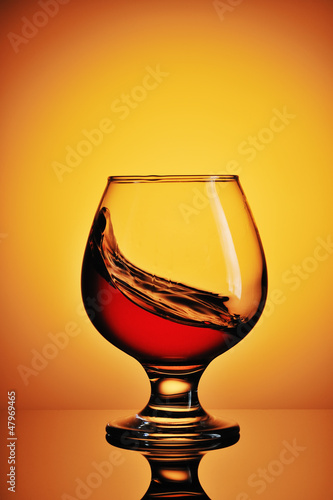 Photo: Glass of cognac on yellow background Glass of cognac on yellow background
