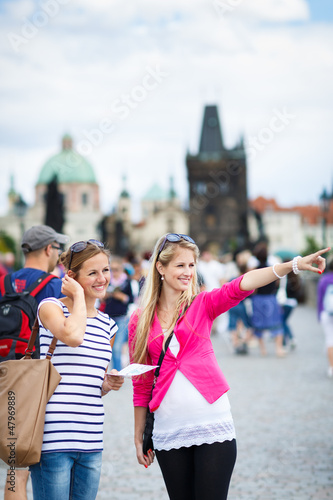 Photo: Two female tourists walking along the Charles Bridge while sight Two female tourists walking along the Charles Bridge while sight