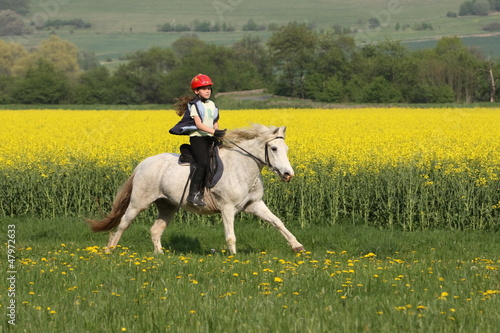 Photo: Mädchen galoppiert vor Rapsfeld Mädchen galoppiert vor Rapsfeld
