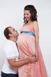 Happy man embracing  pregnant belly of his wife