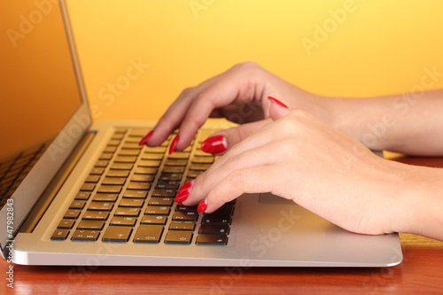 Photo: Detail of female hands using computer on color background Detail of female hands using computer on color background