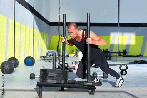 Photo: Crossfit sled push man pushing weights workout Crossfit sled push man pushing weights workout