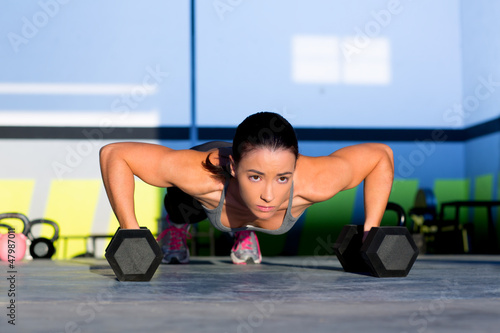 Photo: Gym woman push-up strength pushup with dumbbell Gym woman push-up strength pushup with dumbbell