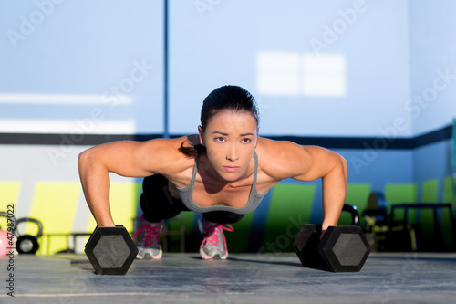 Photo: Gym woman push-up strength pushup with dumbbell Gym woman push-up strength pushup with dumbbell