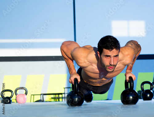 Photo: Gym man push-up strength pushup with Kettlebell Gym man push-up strength pushup with Kettlebell