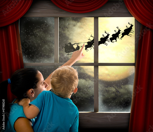 Photo: Woman with child pointing at Santa Claus on sky Woman with child pointing at Santa Claus on sky
