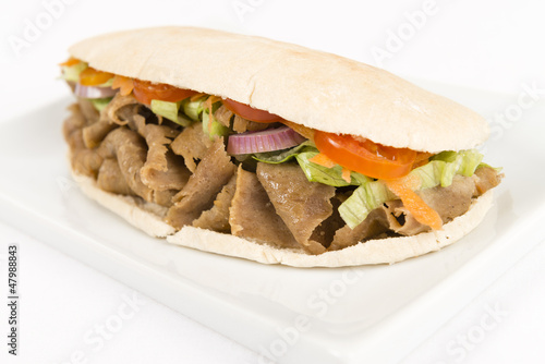 Photo: Donner meat with salad in a flatbread on a white background. Donner meat with salad in a flatbread on a white background.