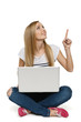 Photo: Woman sitting with laptop on the floor pointing up Woman sitting with laptop on the floor pointing up