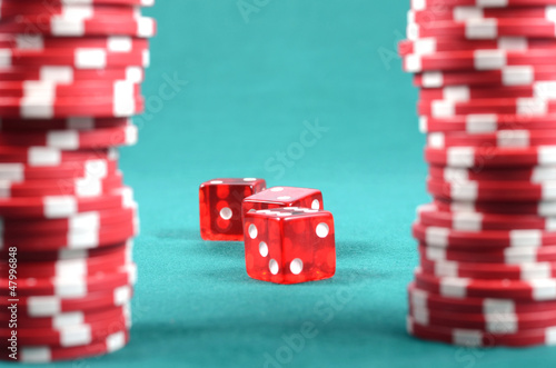 Photo: red poker gambling chips on a green playing table red poker gambling chips on a green playing table