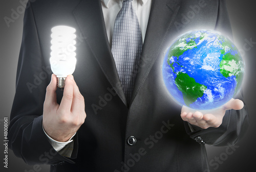 Photo: Businessman holding a light bulb and planet Earth. Businessman holding a light bulb and planet Earth.