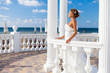 bride posing on beach in white columns on background of blue sky