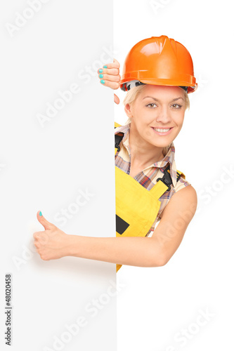 Photo: Female worker giving a thumb up and standing behind panel Female worker giving a thumb up and standing behind panel
