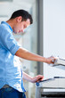 Photo: Handsome young man using a copy machine Handsome young man using a copy machine