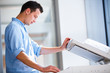 Photo: Handsome young man using a copy machine Handsome young man using a copy machine