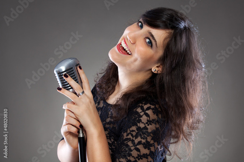 Photo: Attractive young woman with a retro microphone Attractive young woman with a retro microphone