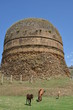 Buddhist stupa with horses grazing in foreground