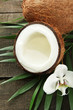 Coconut with leaves and flower, on grey wooden background