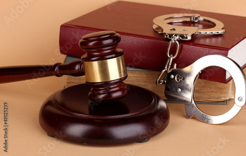 Photo: Gavel, handcuffs and.book on law on beige background Gavel, handcuffs and.book on law on beige background