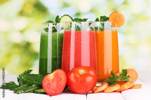 Photo: Fresh vegetable juices on wooden table, on green background Fresh vegetable juices on wooden table, on green background