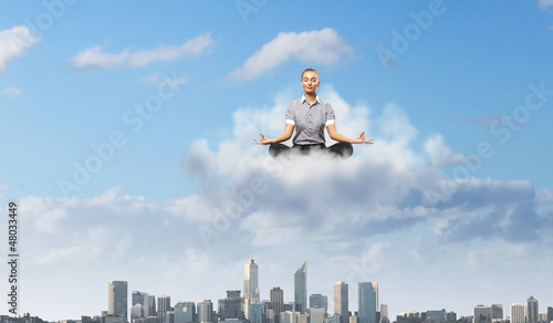 Photo: Businesswoman meditating sitting on the cloud Businesswoman meditating sitting on the cloud