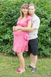 a happy young pregnant woman with her husband rests in a park